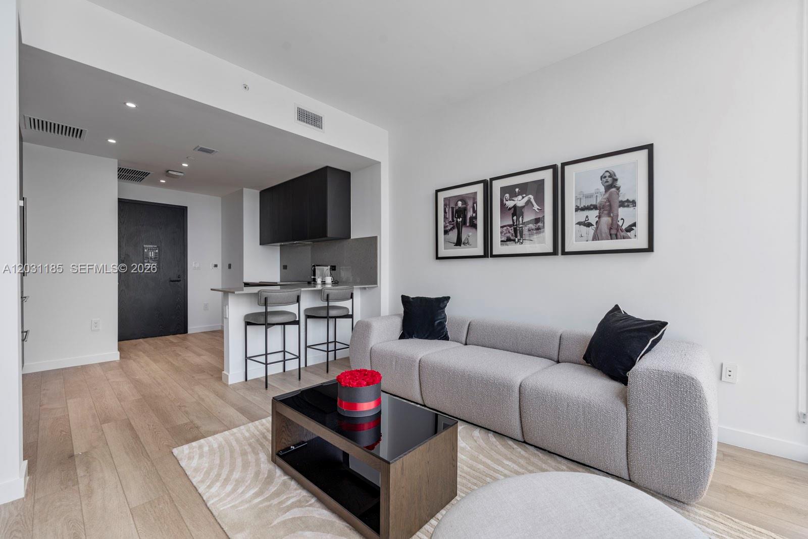 A modern living room features a grey sofa, coffee table, and an open kitchen area — 20 NE 11th Street # 4309, Miami FL 33132, MIAMI, FL
