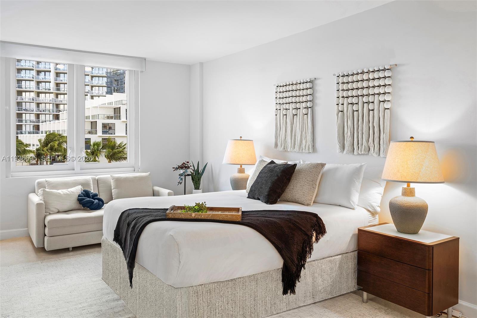 A bedroom features a bed with a dark throw, two bedside lamps, and wall hangings — 2301 Collins Ave # 408, Miami Beach FL 33139, MIAMI BEACH, FL