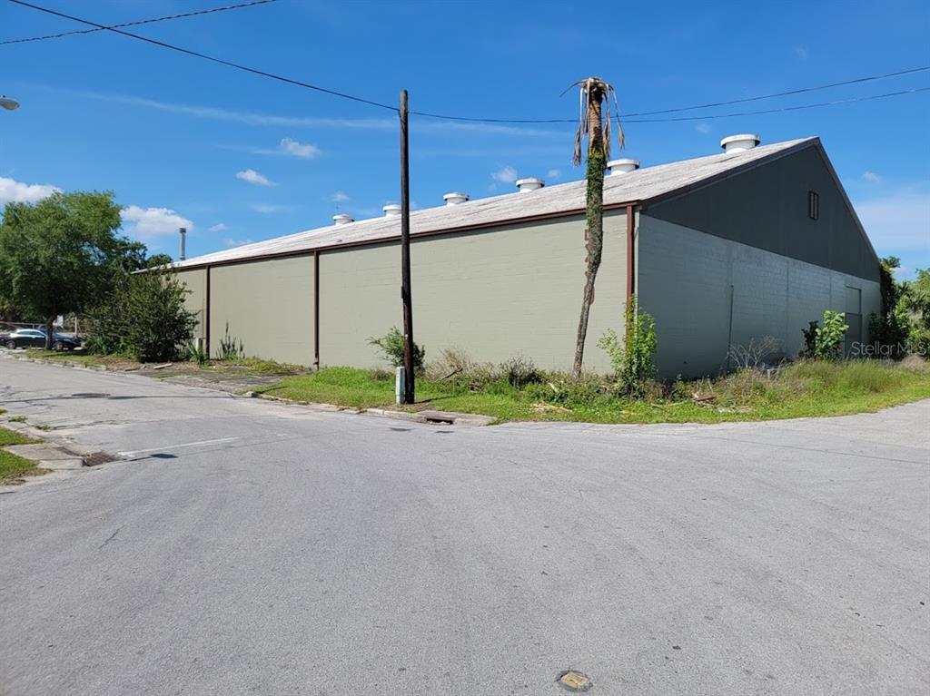 A large, light green industrial warehouse building stands on a corner lot under a blue sky — 530 NW 1ST AVENUE, OCALA, FL
