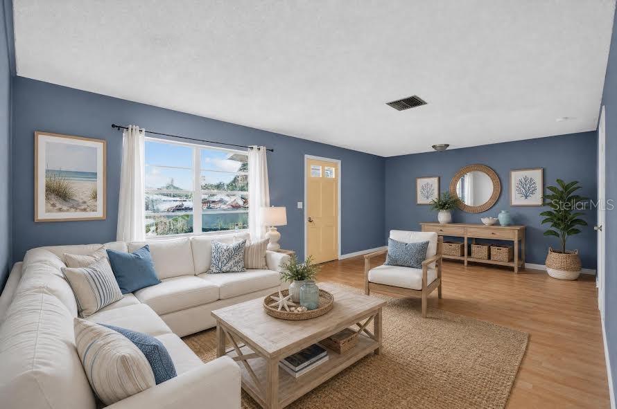 A living room features blue walls, a white sectional sofa, a wooden coffee table, and hardwood floors — 1700 COWAN CIRCLE, TITUSVILLE, FL