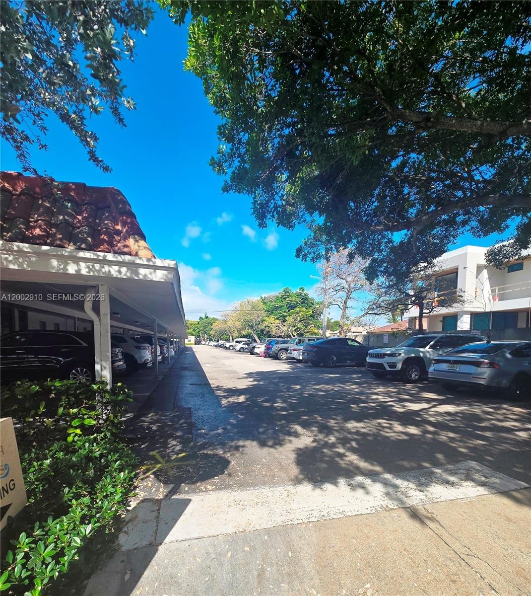 An outdoor parking lot features a covered carport on the left and open parking spaces — 899 E PALMETTO PARK RD, Boca Raton FL 33432, BOCA RATON, FL