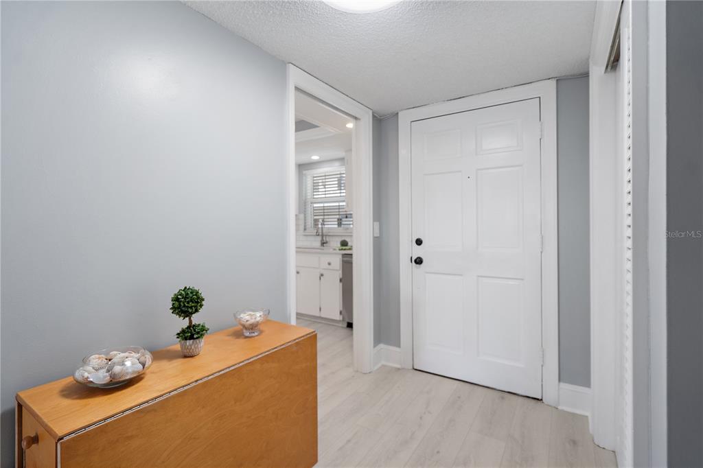 A light-colored entryway features a wooden console table, gray walls, and a white door — 131 BLUFF VIEW DRIVE UNIT 109, BELLEAIR BLUFFS, FL