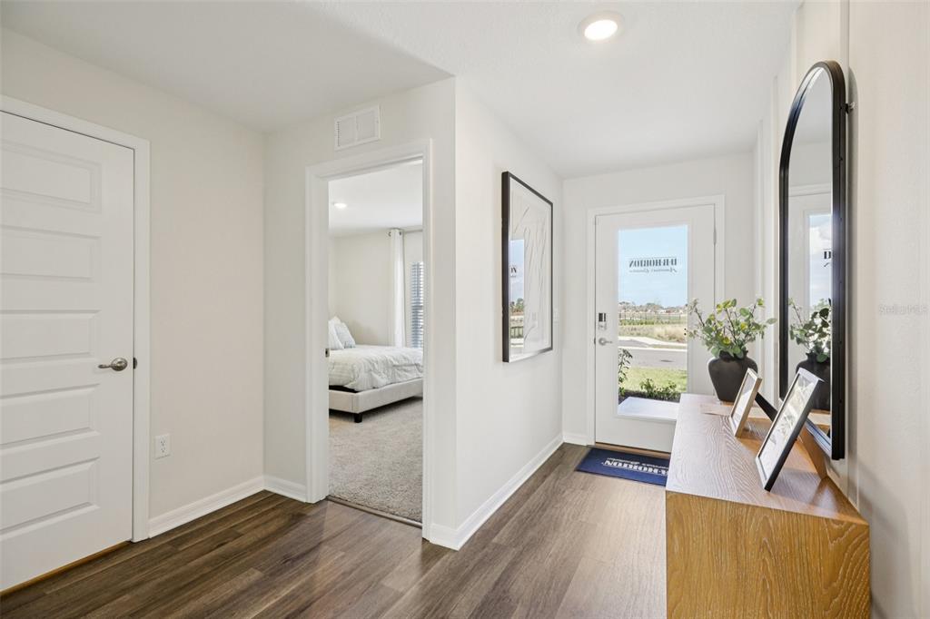 A bright entryway features wood-look flooring, a white door, and a view into a bedroom — 765 GREENWAY BOULEVARD, LAKE WALES, FL