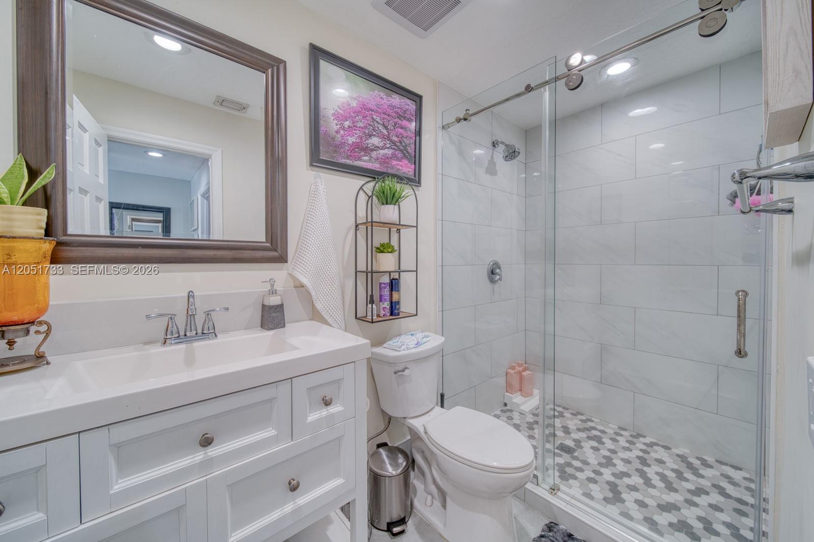 A bathroom features a white vanity, a toilet, and a glass-enclosed shower with tiled walls — 8611 SW 207th Ter, Cutler Bay FL 33189, CUTLER BAY, FL