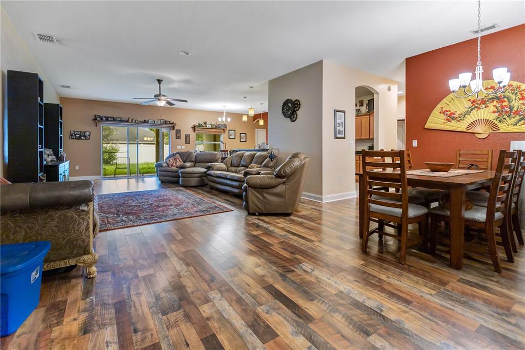 An open-concept living and dining area features wood-look flooring, a red accent wall, and furniture — 2818 WHITNEY STREET, LAKELAND, FL