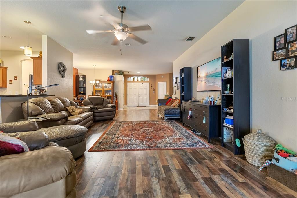 A living room features wood-look flooring, a large area rug, leather furniture, and a television — 2818 WHITNEY STREET, LAKELAND, FL