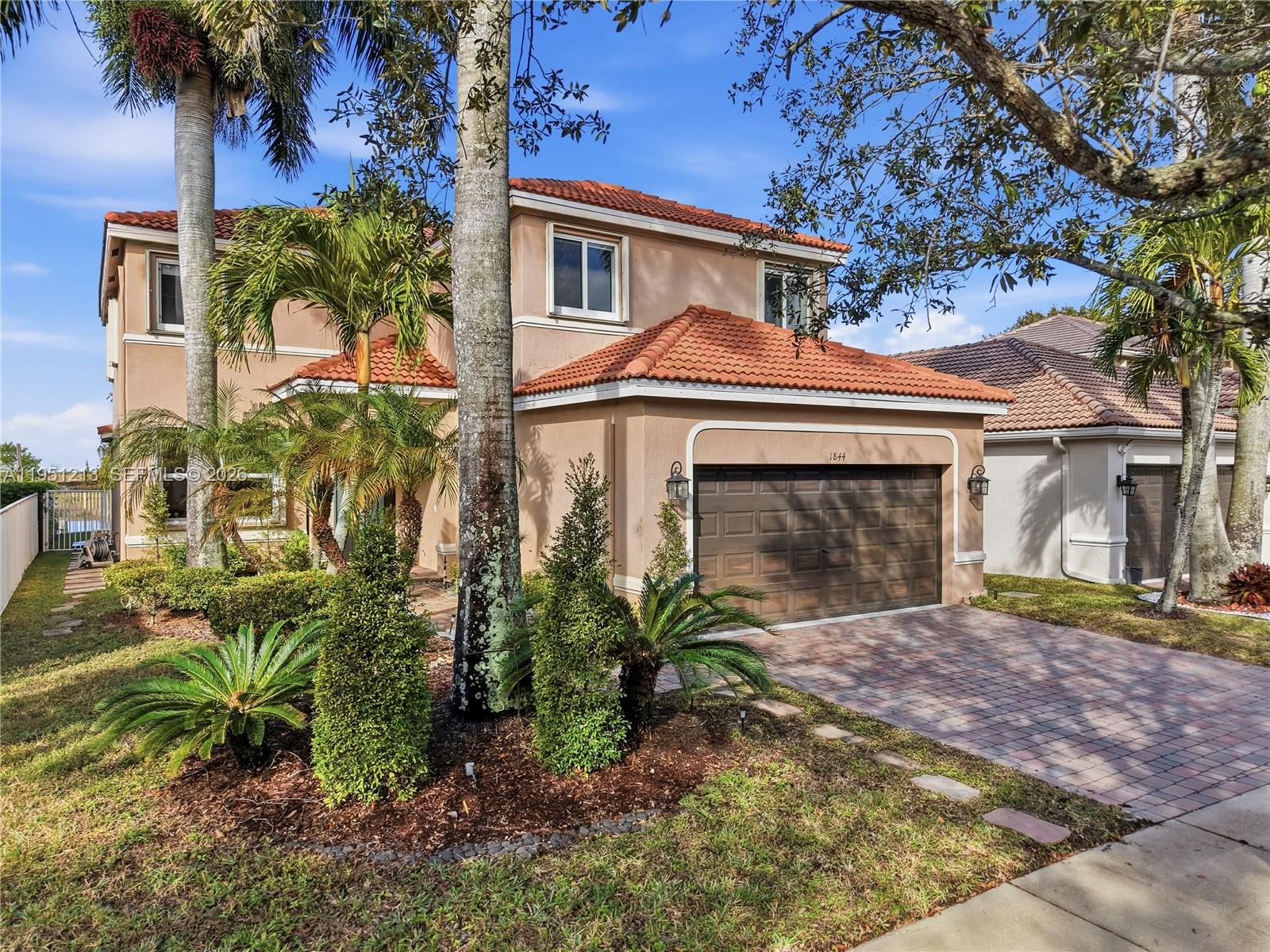A two-story stucco house with a red tile roof and a paved driveway — 1844 Aspen Ln, Weston FL 33327, WESTON, FL