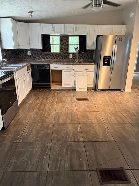 A kitchen features white cabinets, stainless steel appliances, dark tile flooring, and a mosaic backsplash — 11455 NW 110TH AVENUE, REDDICK, FL
