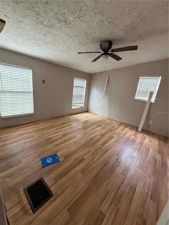 An empty room features wood-look flooring, a ceiling fan, and three windows with blinds — 11455 NW 110TH AVENUE, REDDICK, FL