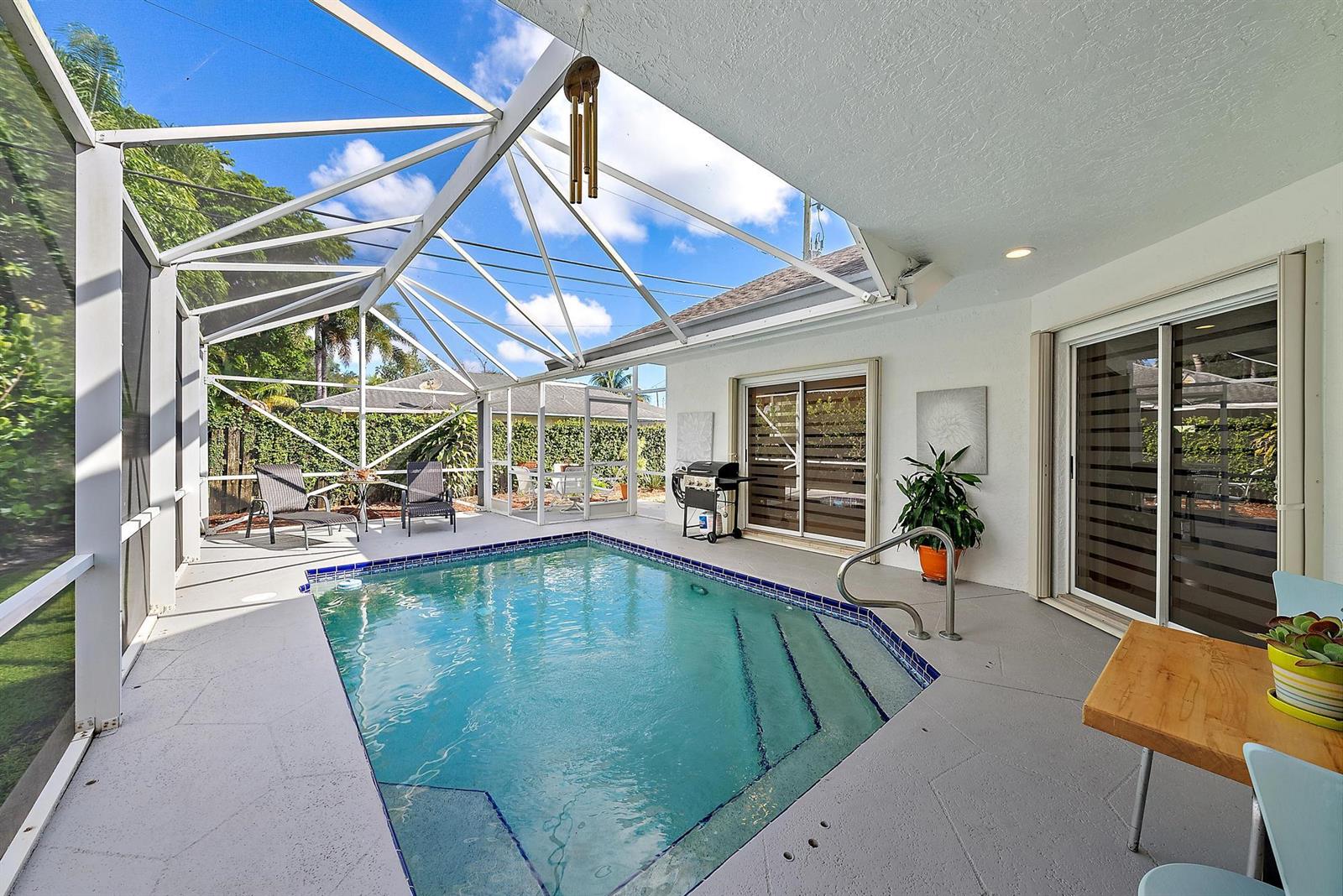 A screened-in patio features a swimming pool, concrete flooring, and sliding glass doors — 6051 Kendrick Street, Jupiter FL 33458, JUPITER, FL