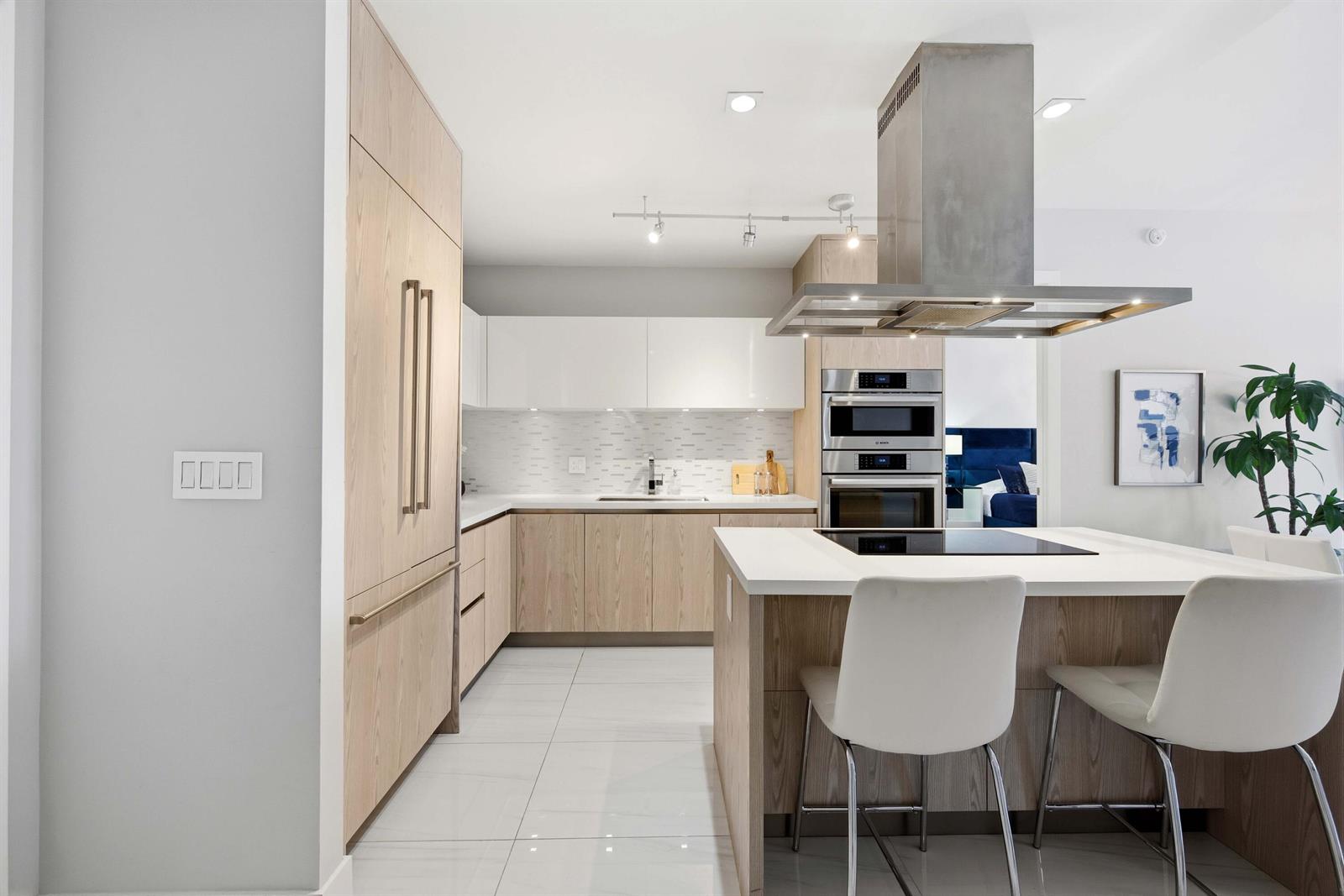 A modern kitchen features light wood cabinetry, white countertops, stainless steel appliances, and a central island — 155 E Boca Raton Road # 313, Boca Raton FL 33432, BOCA RATON, FL