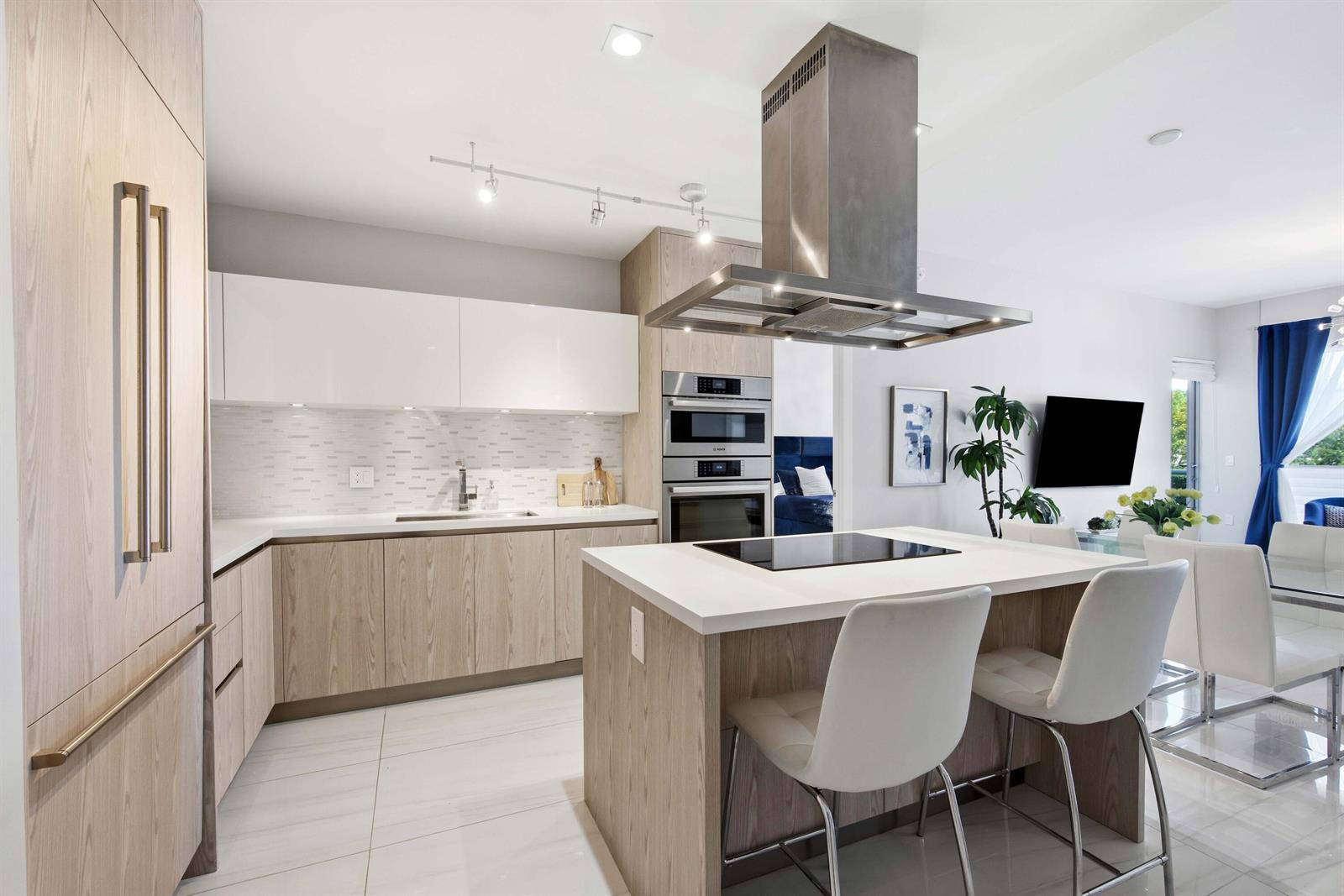 A modern kitchen features light wood cabinetry, white countertops, a center island, and stainless appliances — 155 E Boca Raton Road # 313, Boca Raton FL 33432, BOCA RATON, FL