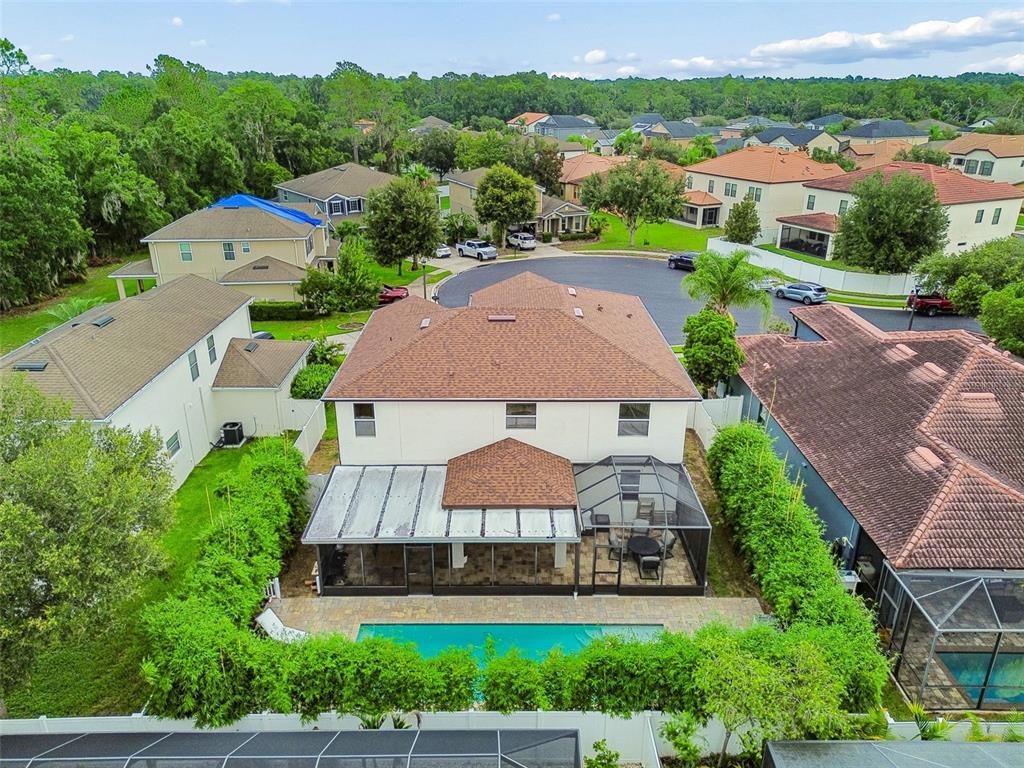 An aerial view of a two-story house with a pool, screened patio, and fenced yard — 23958 TERRACINA COURT, LAND O LAKES, FL