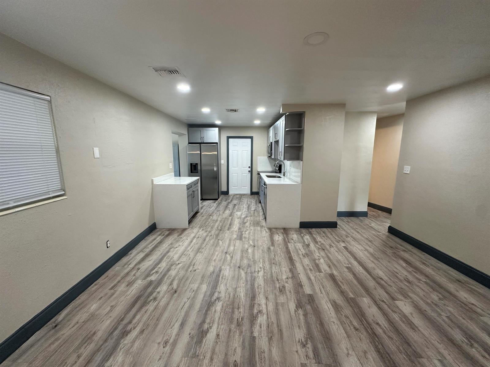 A kitchen features light-colored cabinets, stainless steel appliances, and wood-look flooring in an open space — 2550 NE 7th Terrace, Pompano Beach FL 33064, POMPANO BEACH, FL