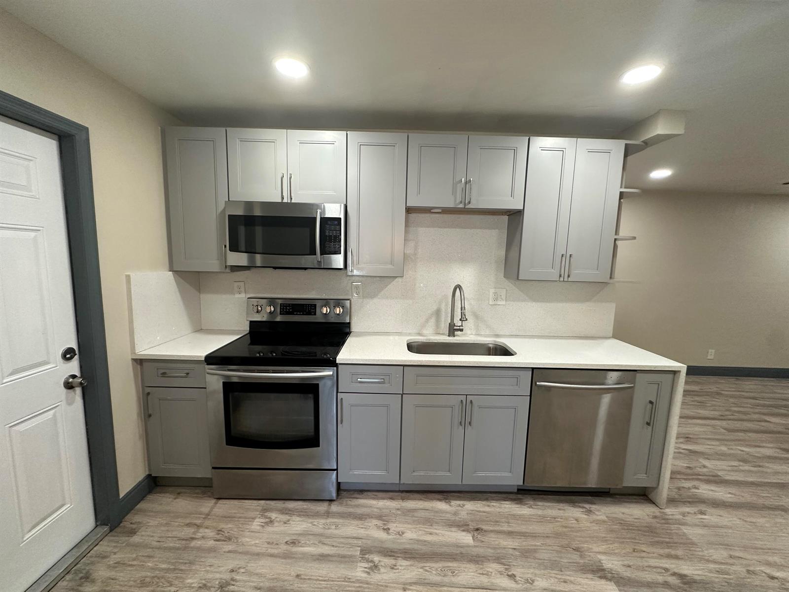 A kitchen features gray cabinets, stainless steel appliances, and white countertops with a backsplash — 2550 NE 7th Terrace, Pompano Beach FL 33064, POMPANO BEACH, FL