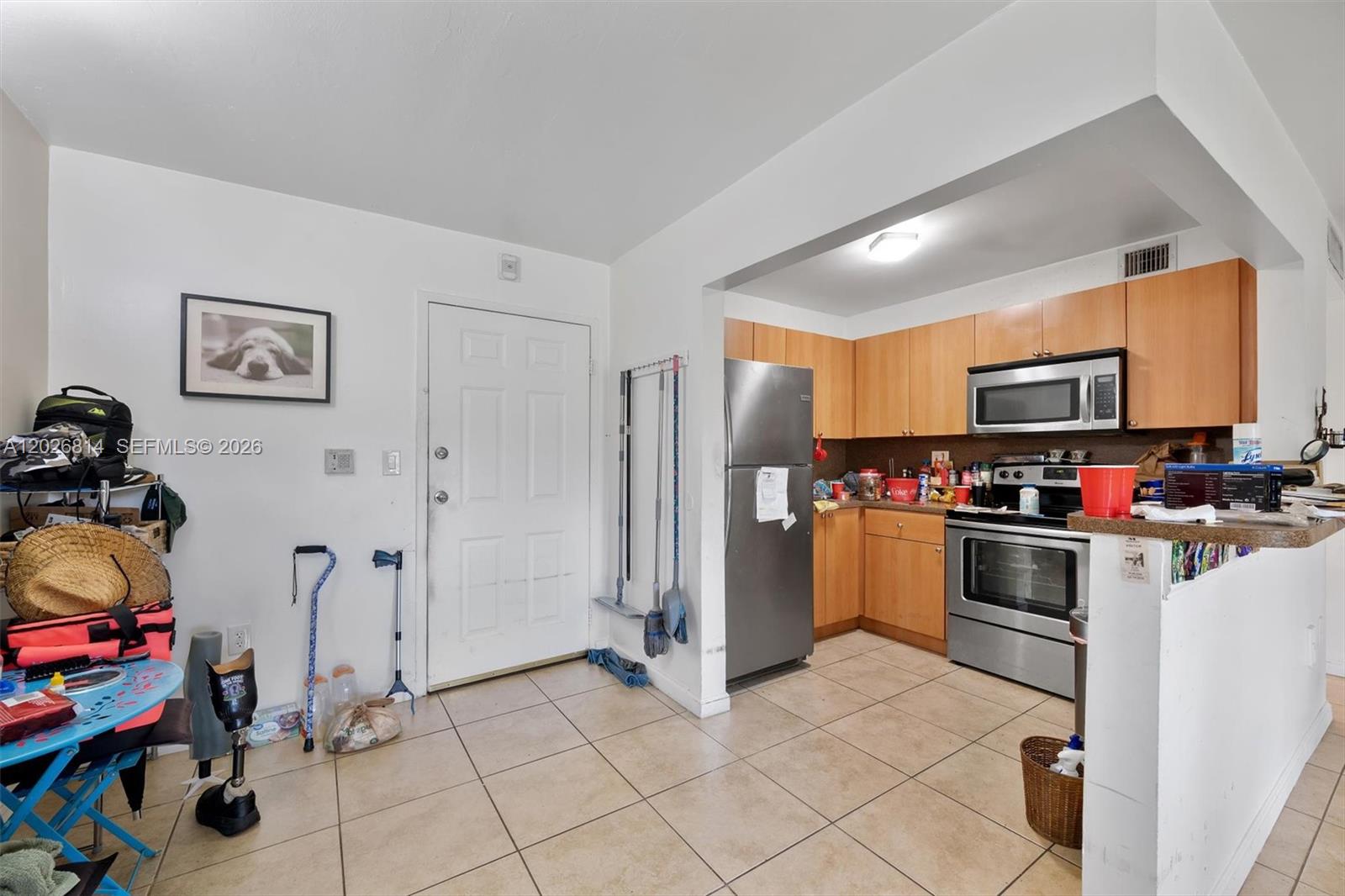 A living room with tile floors, a television on a stand, and a gray armchair — 9445 SW 76th St # U4, Miami FL 33173, MIAMI, FL