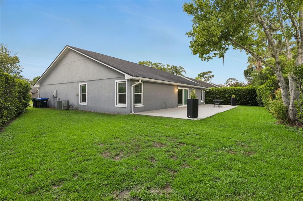 The exterior of a gray house features a concrete patio and a grassy backyard — 2011 EXCALIBUR DRIVE, ORLANDO, FL