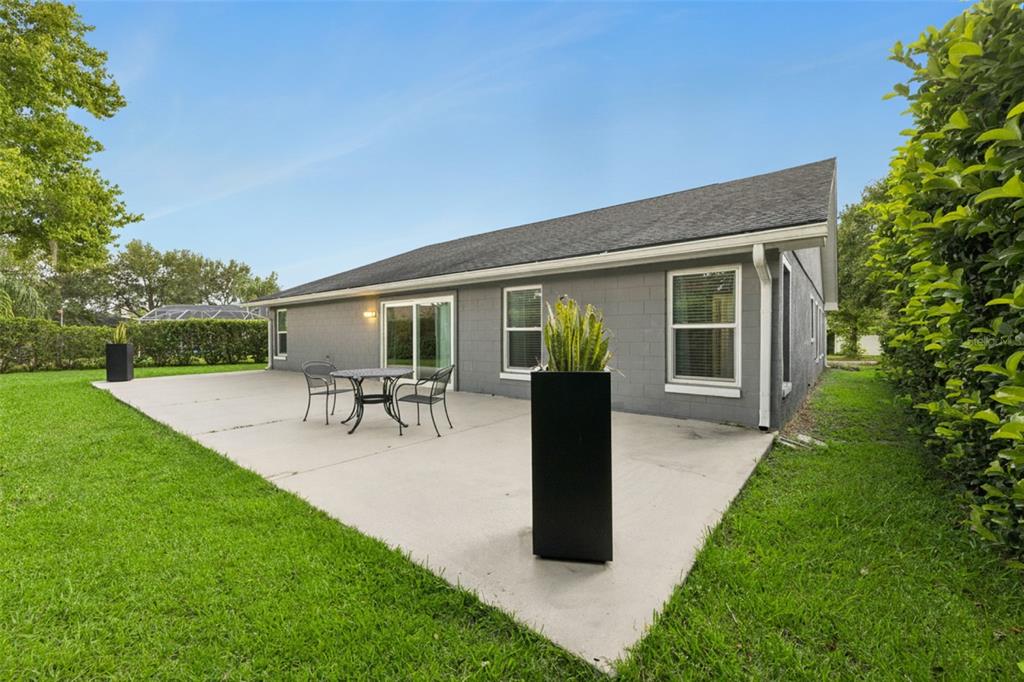 A gray concrete block house with a patio, outdoor furniture, and a large grassy yard — 2011 EXCALIBUR DRIVE, ORLANDO, FL