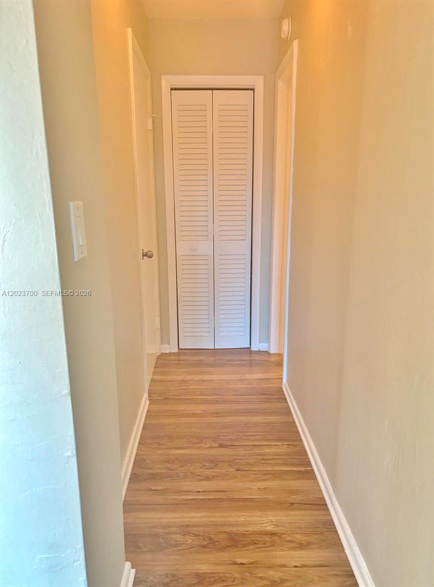 A narrow hallway features light wood-look flooring and a white bi-fold closet door — 2201 Brickell Ave # 61, Miami FL 33129, MIAMI, FL