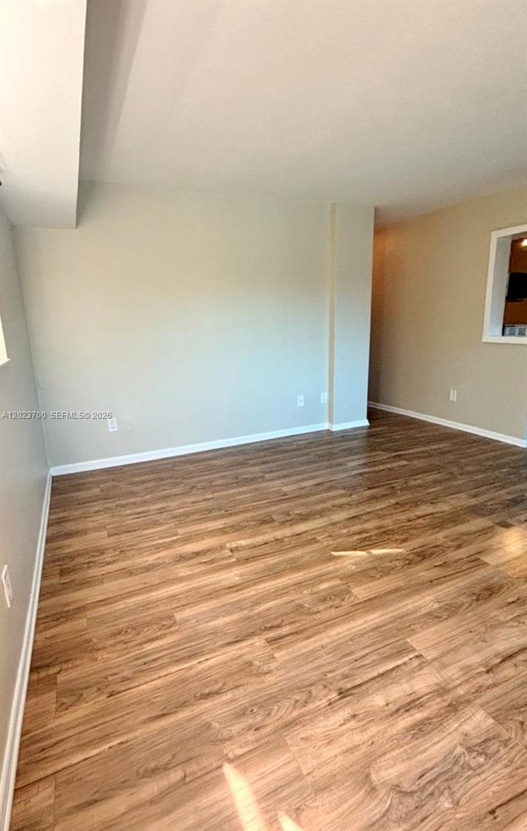 An empty room features light-colored walls and wood-look laminate flooring — 2201 Brickell Ave # 61, Miami FL 33129, MIAMI, FL