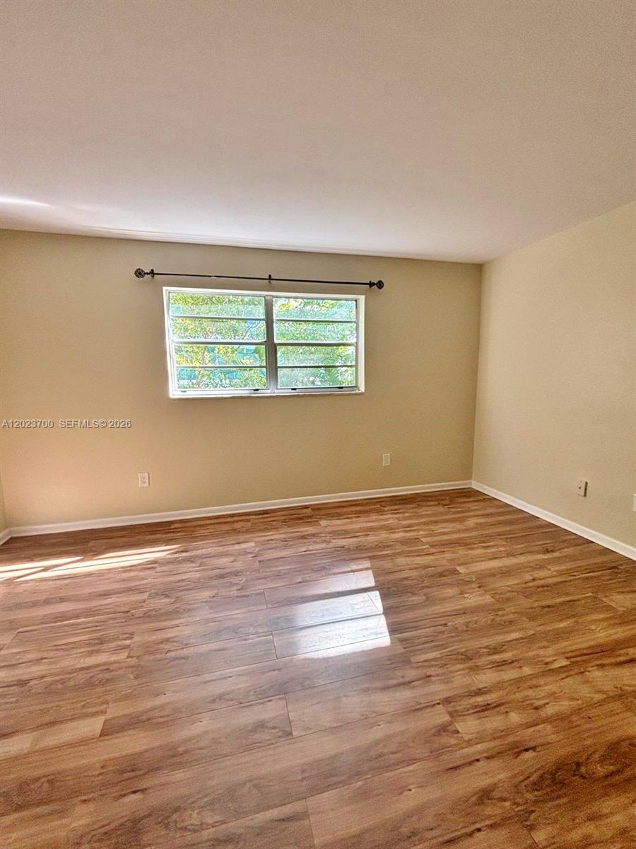 An empty room features light-colored walls, a single window, and wood-look flooring — 2201 Brickell Ave # 61, Miami FL 33129, MIAMI, FL