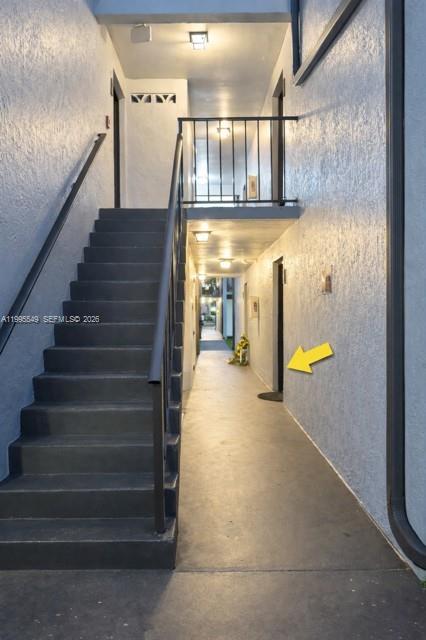 An outdoor stairwell leads to a covered walkway with apartment doors and overhead lighting — 7423 SW 152ND AVE # 103, Miami FL 33193, MIAMI, FL