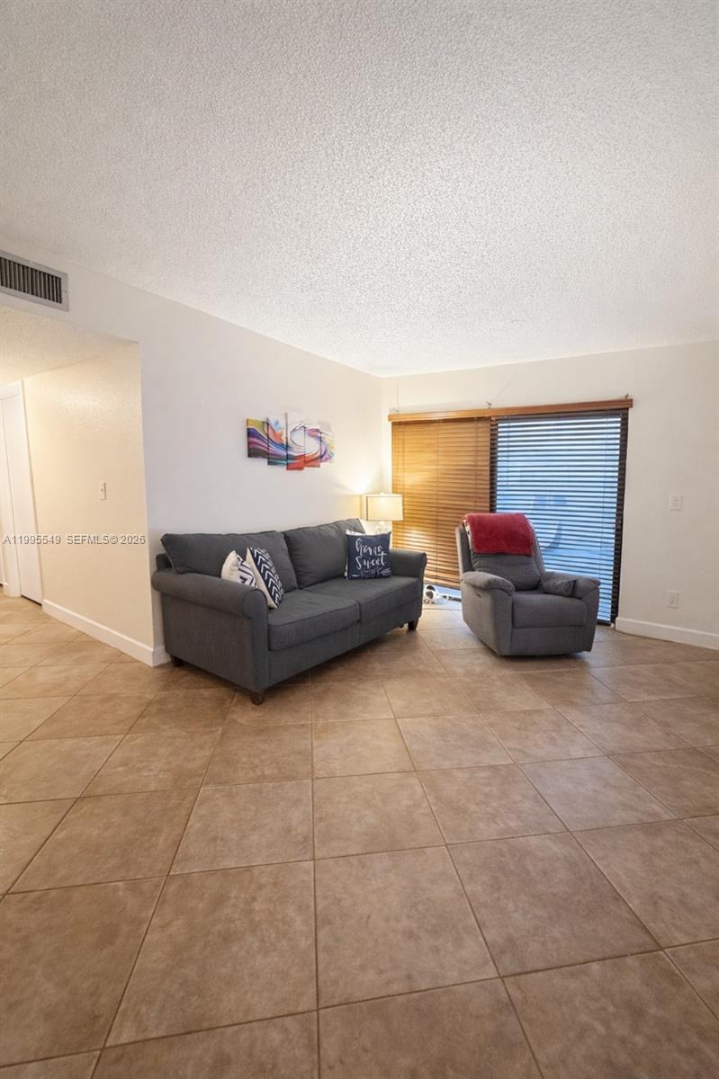 A living room features a gray sofa, a matching recliner, and tile flooring — 7423 SW 152ND AVE # 103, Miami FL 33193, MIAMI, FL