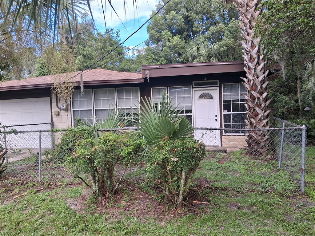 A single-story house with a brown roof, white front door, and a chain-link fence — 1326 NW 14TH AVENUE, GAINESVILLE, FL