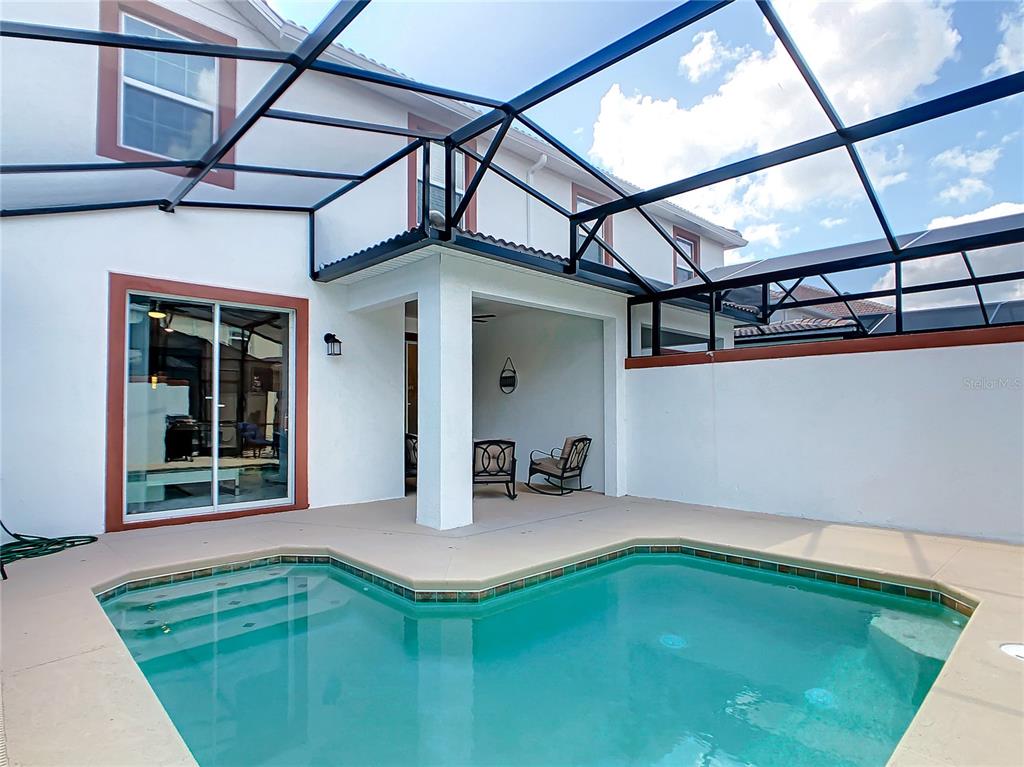 A swimming pool sits on a patio enclosed by a screened-in lanai — 4807 DEDICATION STREET, KISSIMMEE, FL