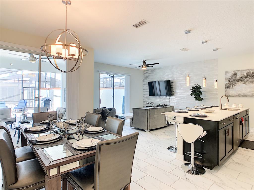 An open-concept living and dining area features a modern kitchen island, tiled floors, and furniture — 4807 DEDICATION STREET, KISSIMMEE, FL