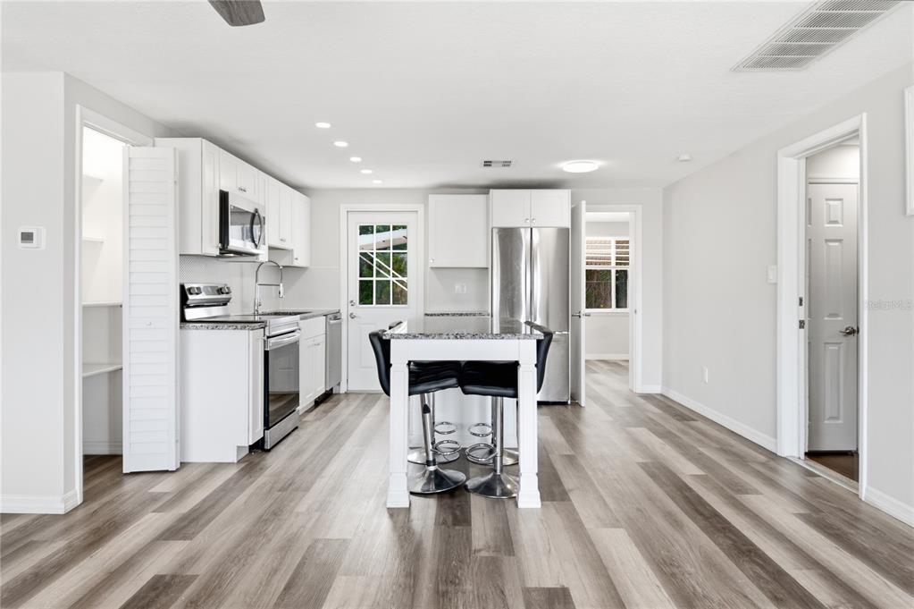 A kitchen with white cabinets, stainless steel appliances, a center island, and wood-look flooring — 4810 GUARDIAN AVENUE, HOLIDAY, FL