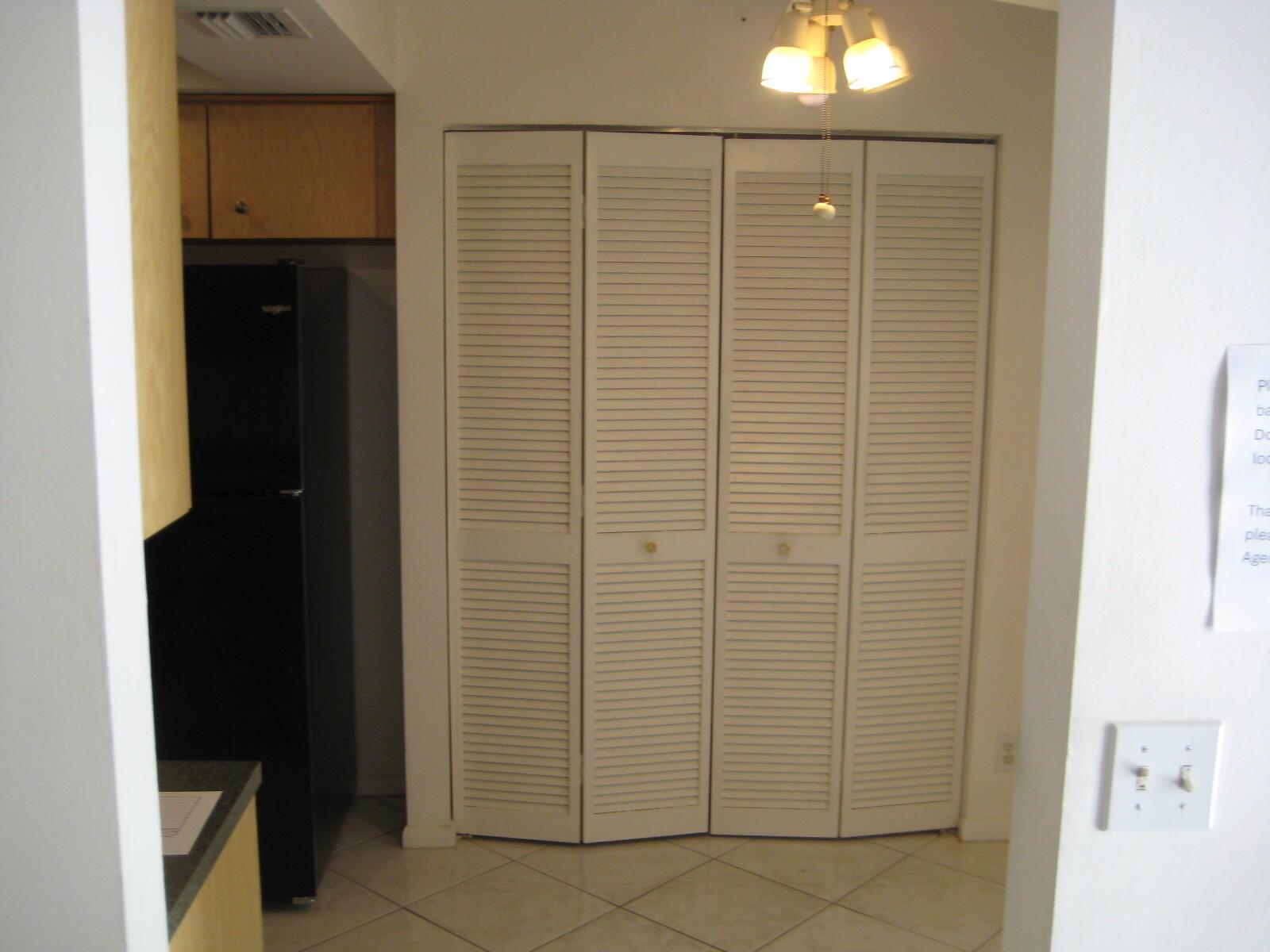 A kitchen area features a black refrigerator, light wood cabinets, and white louvered closet doors — 5153 Oak Hill Road # 511, Delray Beach FL 33484, DELRAY BEACH, FL