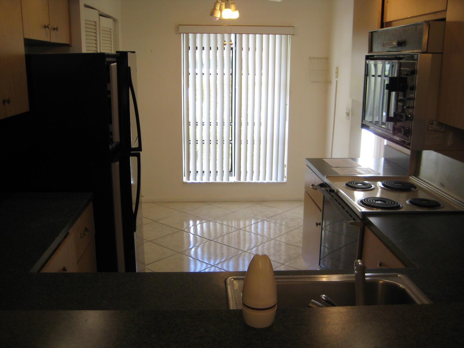A kitchen features a black refrigerator, a wall oven, a stovetop, and tiled flooring — 5153 Oak Hill Road # 511, Delray Beach FL 33484, DELRAY BEACH, FL