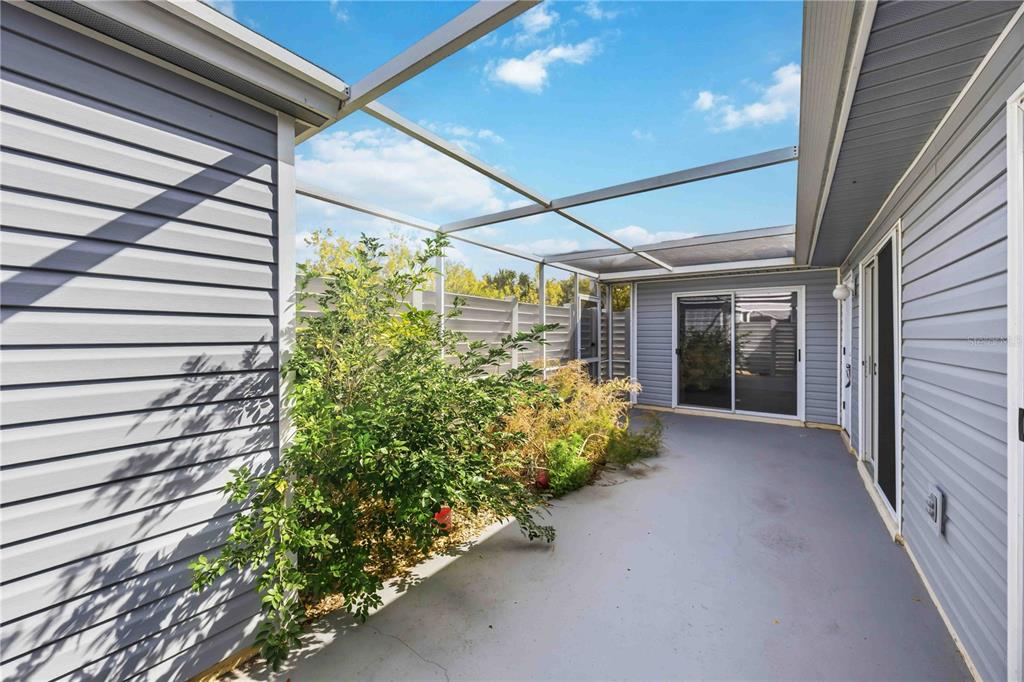 A screened-in patio with gray siding, a concrete floor, and a small garden area — 3300 LOVELAND BOULEVARD UNIT 2501, PUNTA GORDA, FL