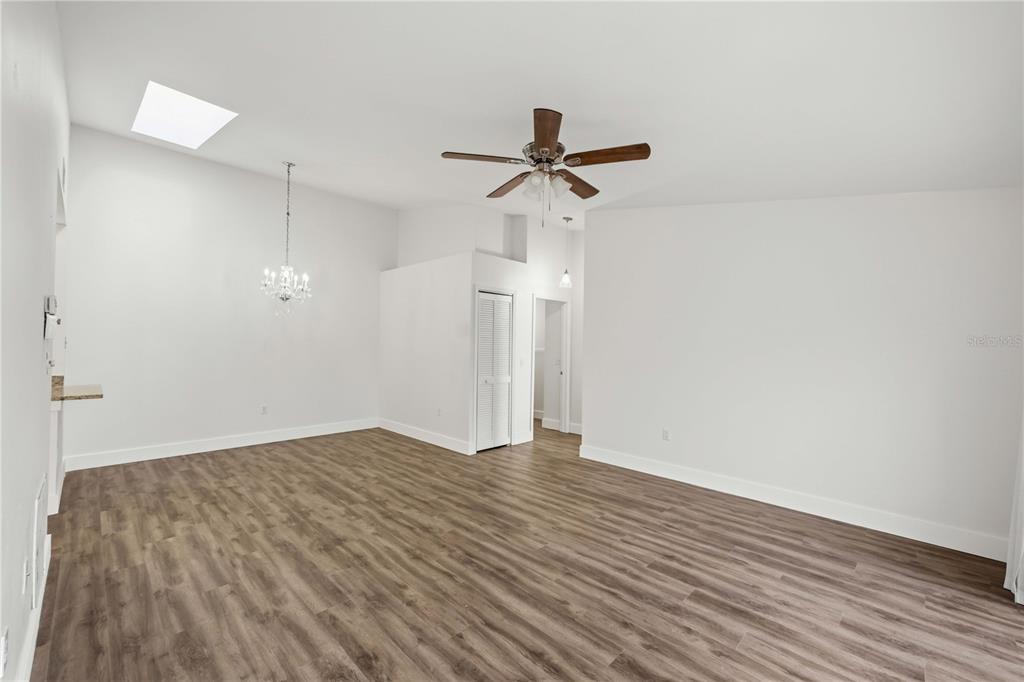 An empty room with wood-look flooring, a ceiling fan, a skylight, and a chandelier — 3300 LOVELAND BOULEVARD UNIT 2501, PUNTA GORDA, FL