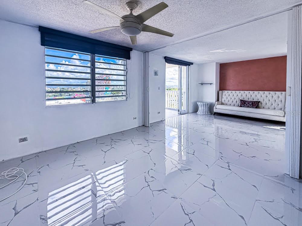 A living room features white marble-look tile flooring, a ceiling fan, and a tufted sofa — MIRAMAR TOWERS 721 HERNANDEZ ST. UNIT A, SAN JUAN, PR