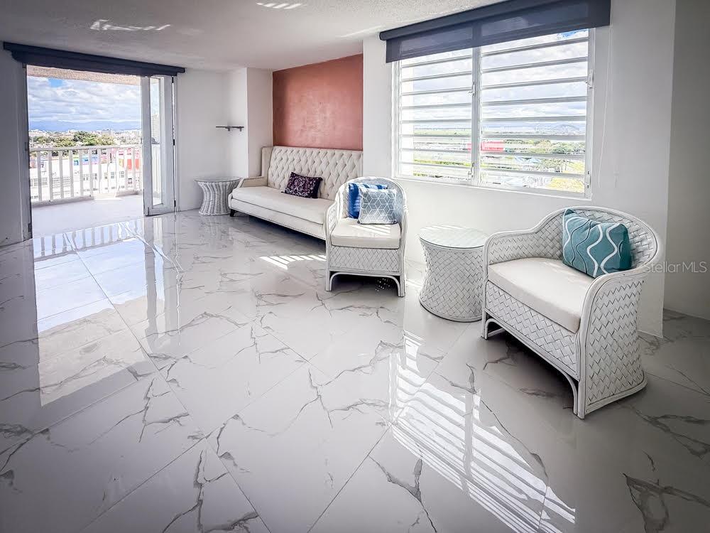 A living room features white marble tile floors, wicker furniture, and a balcony with city views — MIRAMAR TOWERS 721 HERNANDEZ ST. UNIT A, SAN JUAN, PR