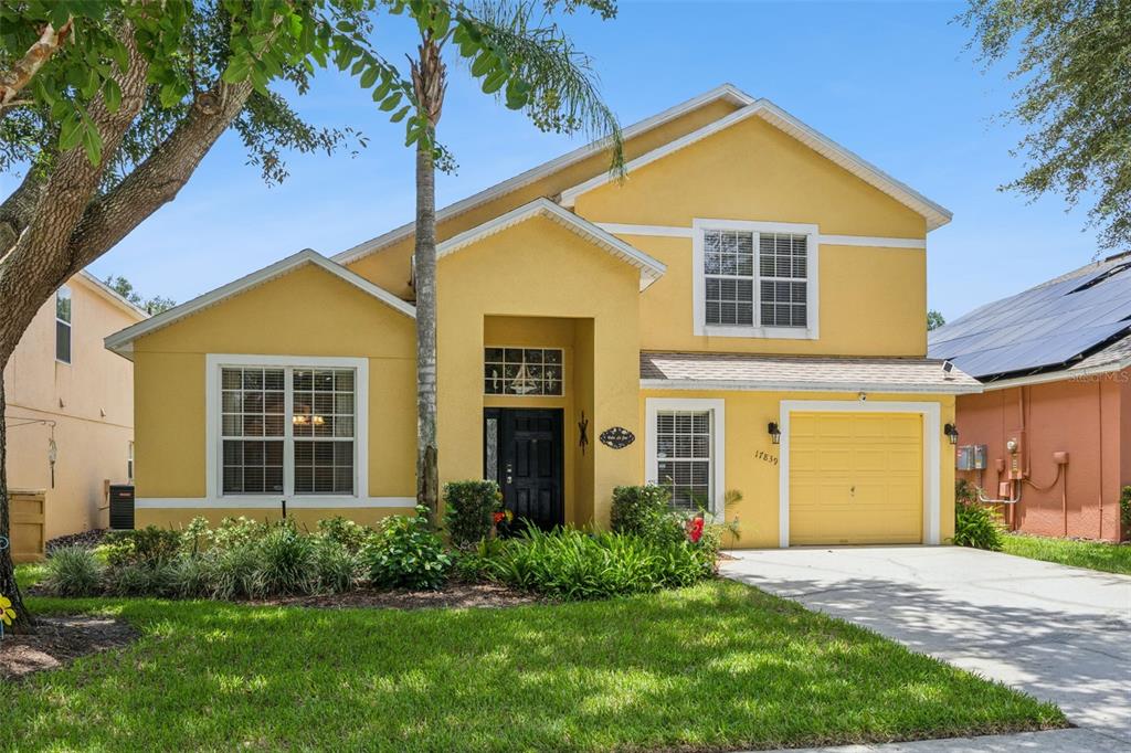 A two-story yellow house with a single-car garage and a front lawn — 17839 WOODCREST WAY, CLERMONT, FL