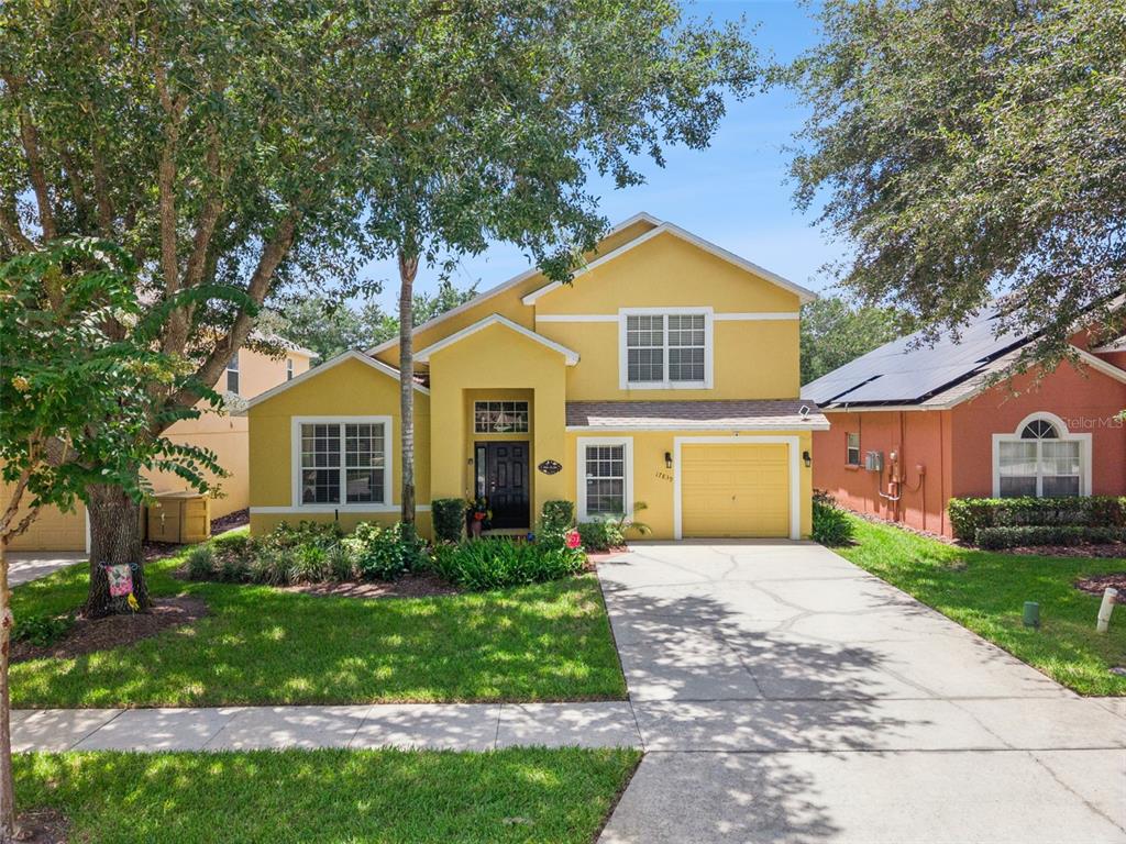 A yellow two-story house with a single-car garage and a concrete driveway — 17839 WOODCREST WAY, CLERMONT, FL