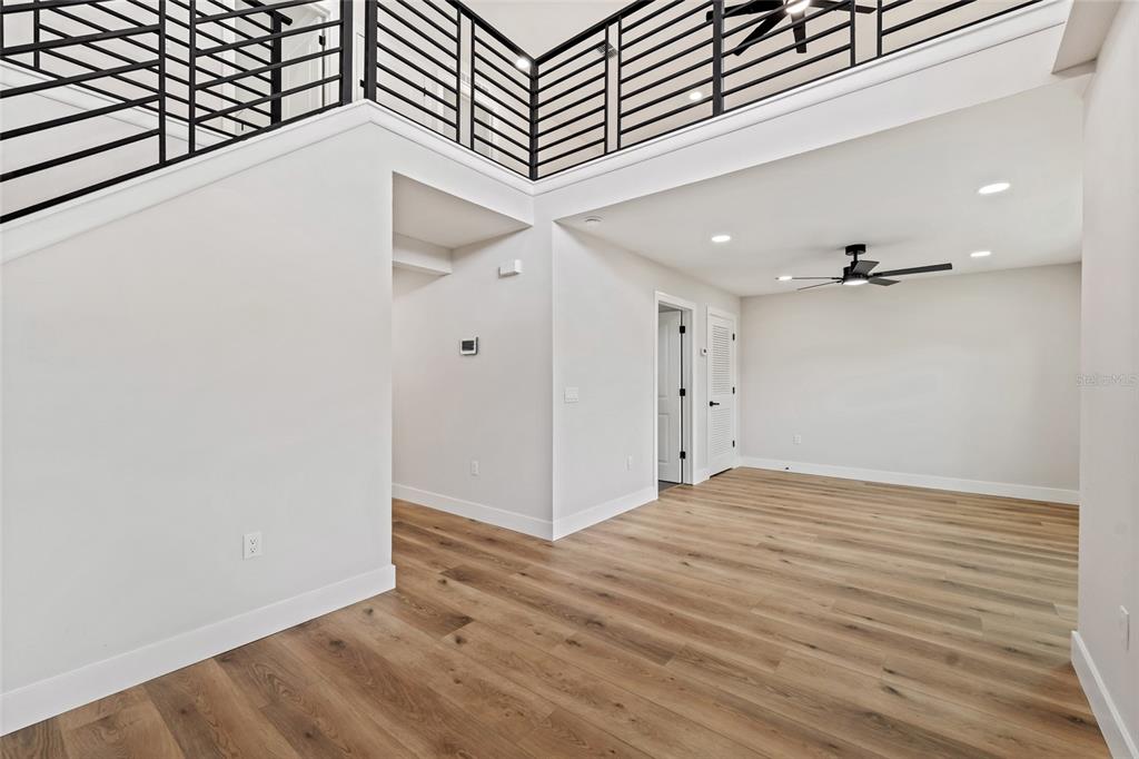An interior view shows a room with light wood floors, white walls, and a staircase — 2960 WHITE MAGNOLIA LOOP, CLERMONT, FL