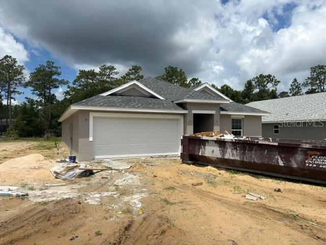 A newly constructed single-story house with a two-car garage and a large construction dumpster outside — 7744 SW 180TH CIRCLE, DUNNELLON, FL