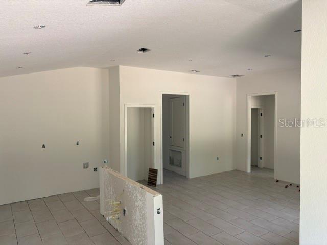 An interior view of an unfinished room with light-colored tile flooring and white walls — 7744 SW 180TH CIRCLE, DUNNELLON, FL