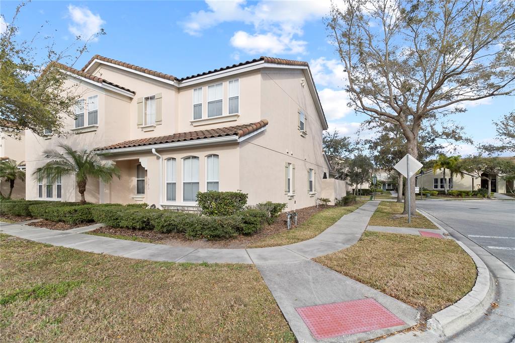 A two-story beige stucco house with a tiled roof sits on a corner lot — 3173 AQUA VIRGO LOOP UNIT 18, ORLANDO, FL