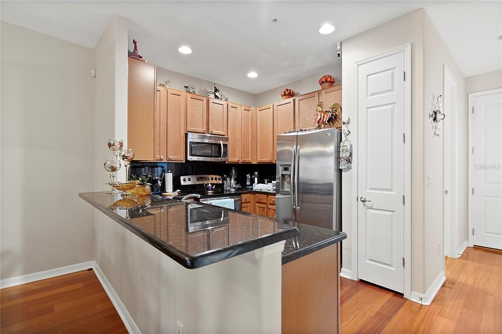 A kitchen features wood cabinets, stainless steel appliances, and a dark granite breakfast bar — 3173 AQUA VIRGO LOOP UNIT 18, ORLANDO, FL