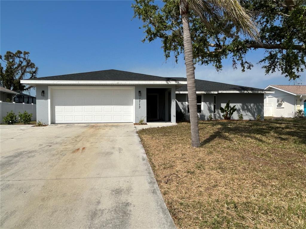 A single-story gray house with a two-car garage and a palm tree in the front yard — 1713 WALDEN COURT, ENGLEWOOD, FL