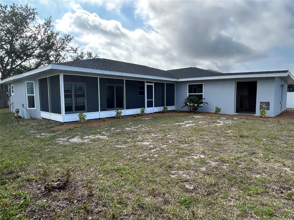 The exterior of a gray house features a large screened-in porch and a backyard — 1713 WALDEN COURT, ENGLEWOOD, FL