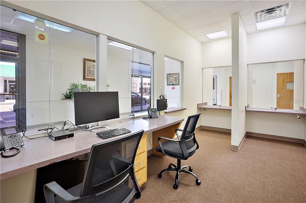 An office space features a desk with two chairs, glass partitions, and carpeted flooring — 711 W MAIN STREET, LEESBURG, FL