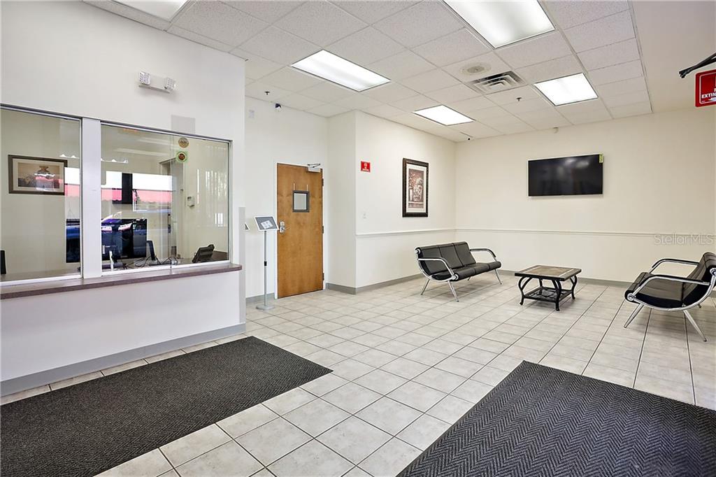 A waiting room features tiled floors, a reception window, black seating, and a wall-mounted television — 711 W MAIN STREET, LEESBURG, FL