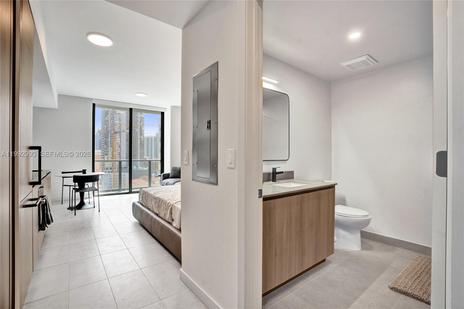 A modern studio apartment features a bathroom, kitchen area, and a bed near a balcony — 121 NE 5th Street # 1404, Miami FL 33132, MIAMI, FL