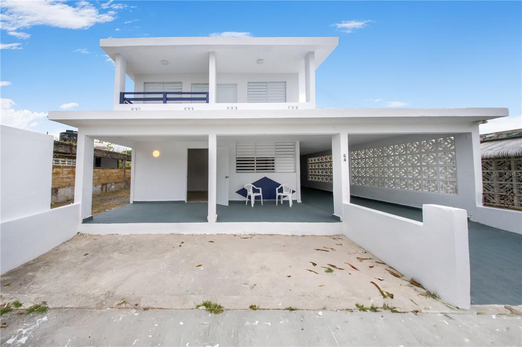 A two-story white house with a covered front porch, carport, and decorative concrete block walls — G4 AVENIDA A, FAJARDO, PR